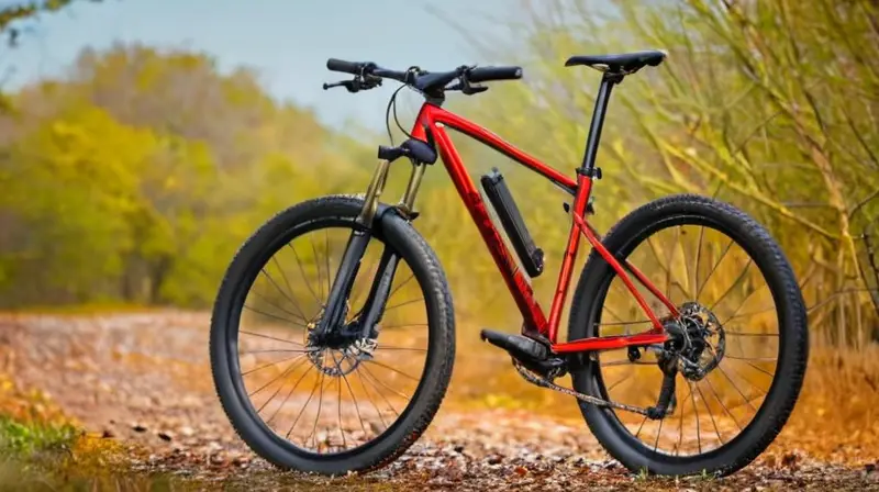 Una bicicleta ligera y elegante con detalles en negro mate y rojo, diseñada para destacar en un entorno natural