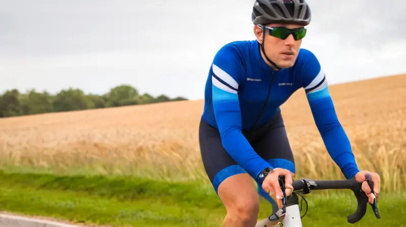 Jersey de ciclismo ajustado en azul marino con detalles reflectantes, paneles de malla, y bolsillos traseros, que evoca movimiento y preparación para el ciclismo en clima fresco